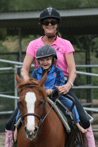 Diane Schott and little boy enjoying a pony ride